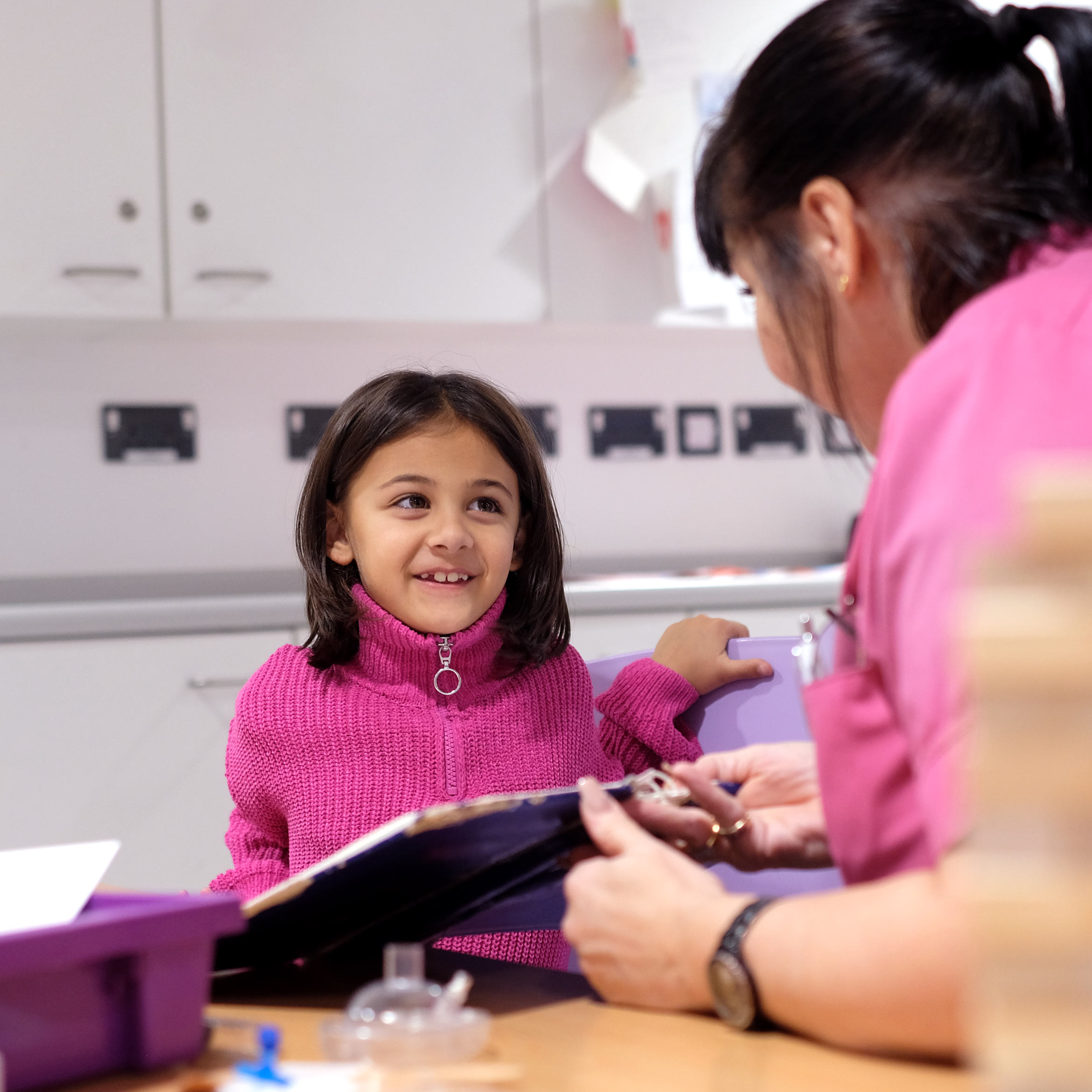 Nurse helping young girl read a book.